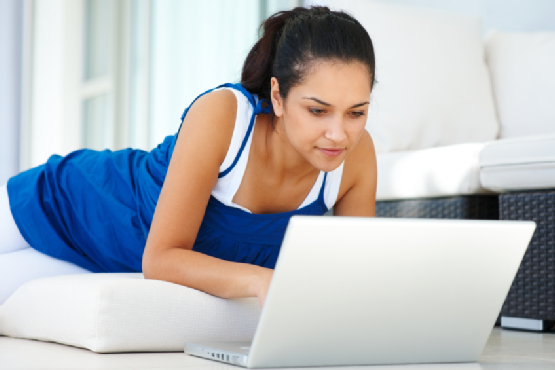 Beautiful young girl using a laptop while lying at home