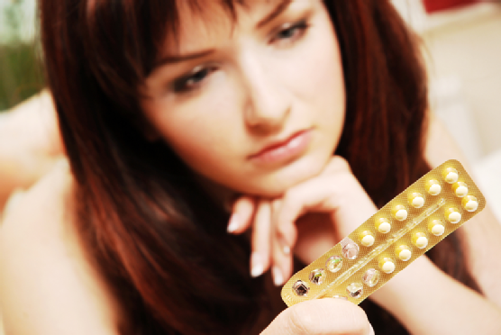 Young woman looking at her contraceptive pills